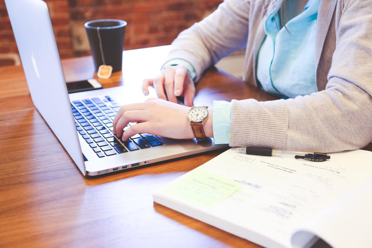 a landlord in a brown sweater prepares an eviction notice on their laptop for a tenant